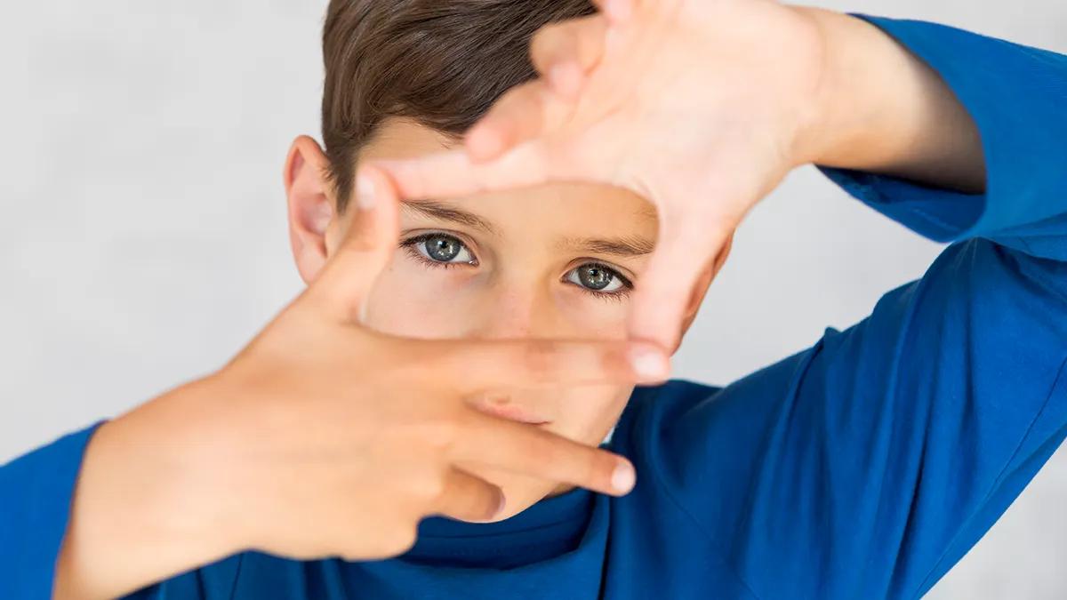 pose seorang anak kecil menggunakan kaos berwarna biru, pose berfokus pada mata anak laki-laki tersebut