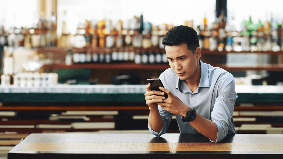 seorang pekerja pria berbaju biru muda sedang menatap layar smartphone