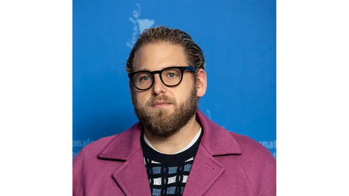 foto Jonah Hill menggunakan jas ungu dan kacamata tebal yang kurang proporsional dengan bentuk wajahnya